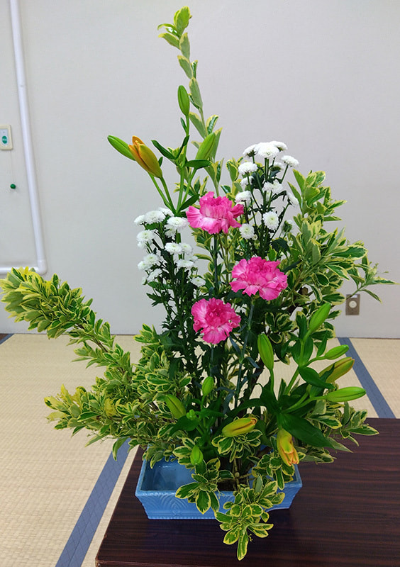 白、ピンク、オレンジ、緑が映える生け花の拡大写真です。